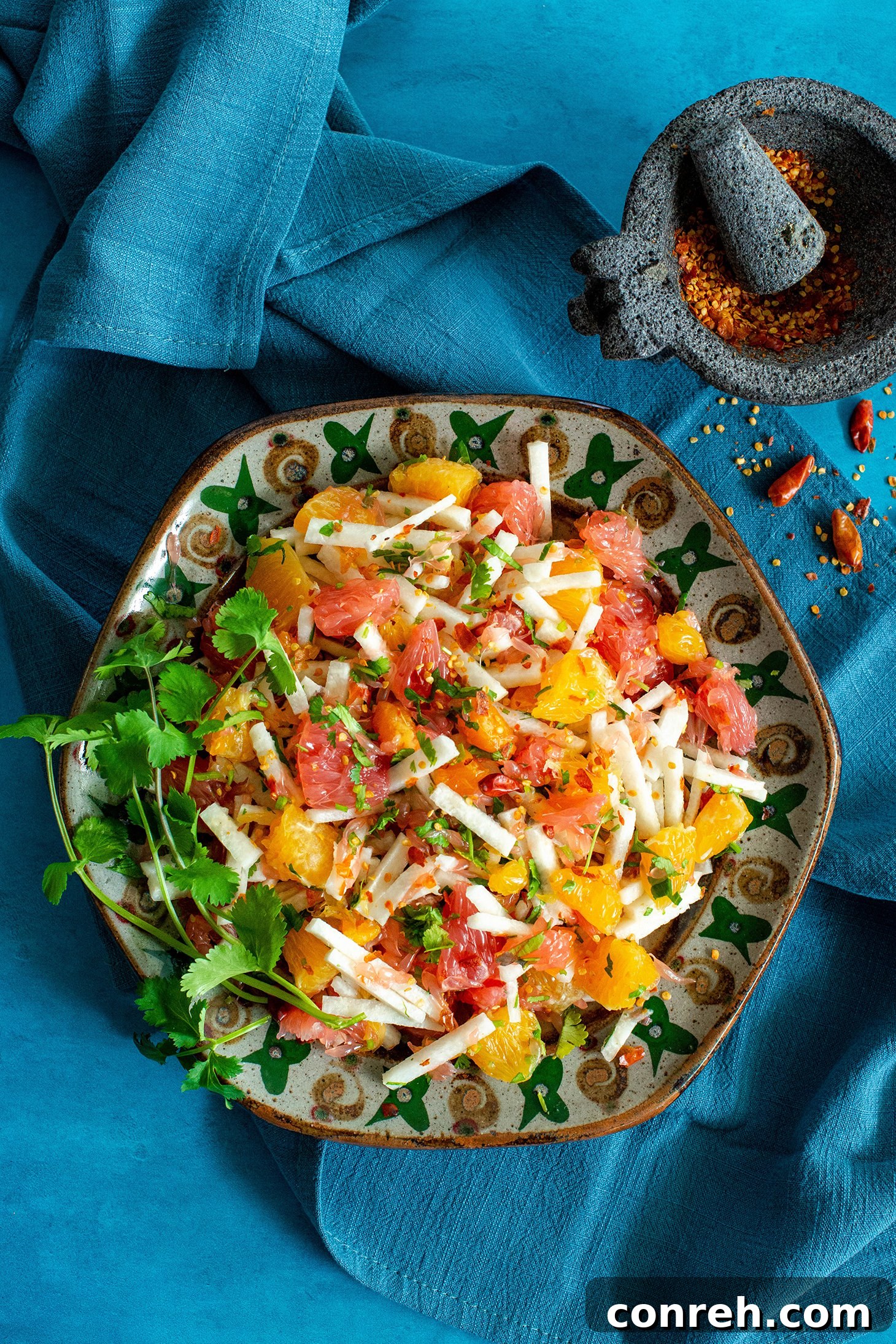 Vibrant Xe'ek fruit salad with fresh citrus and jicama, garnished with cilantro and chili.