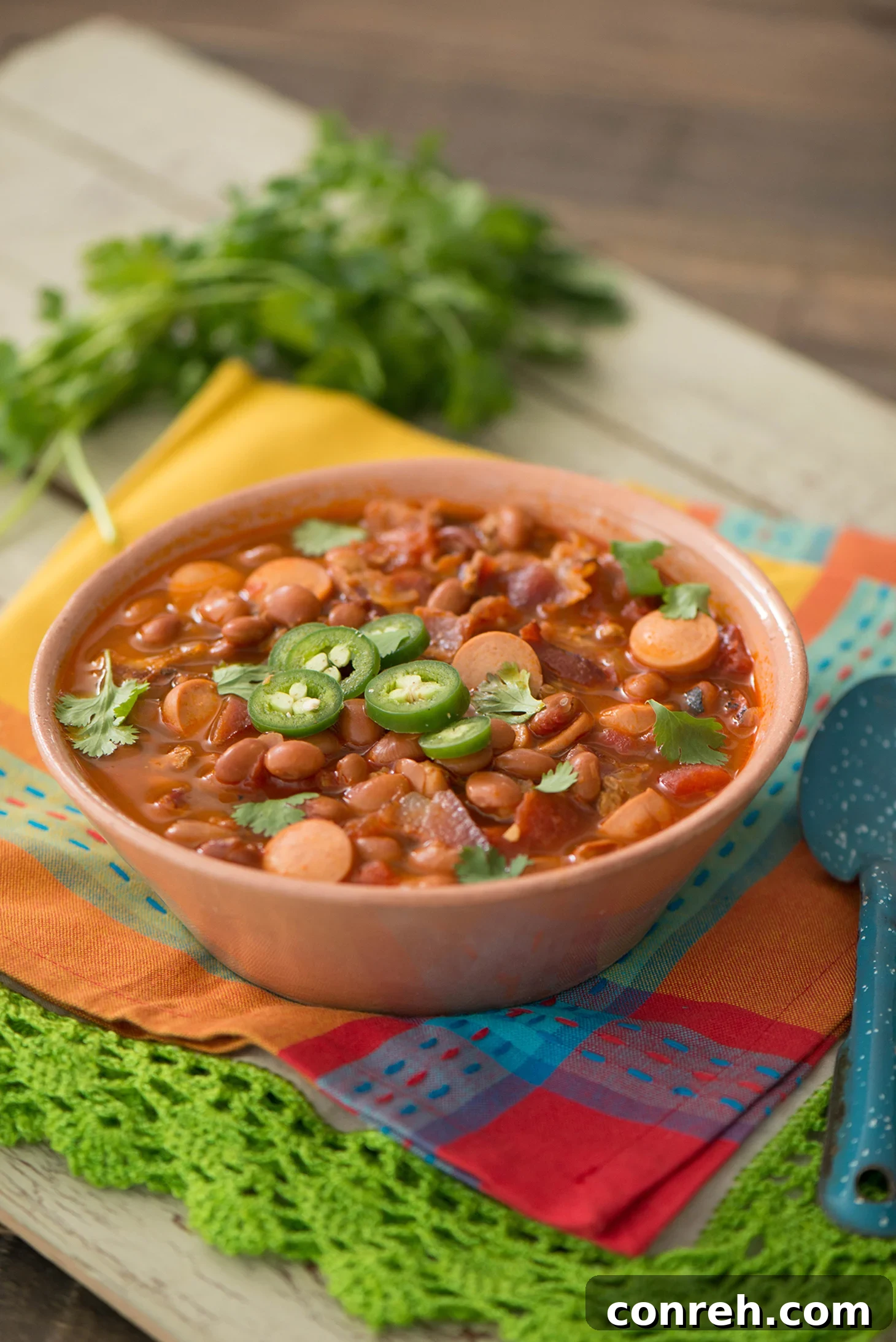 A steaming bowl of Frijoles Charros, garnished with fresh cilantro and lime, ready to be served.
