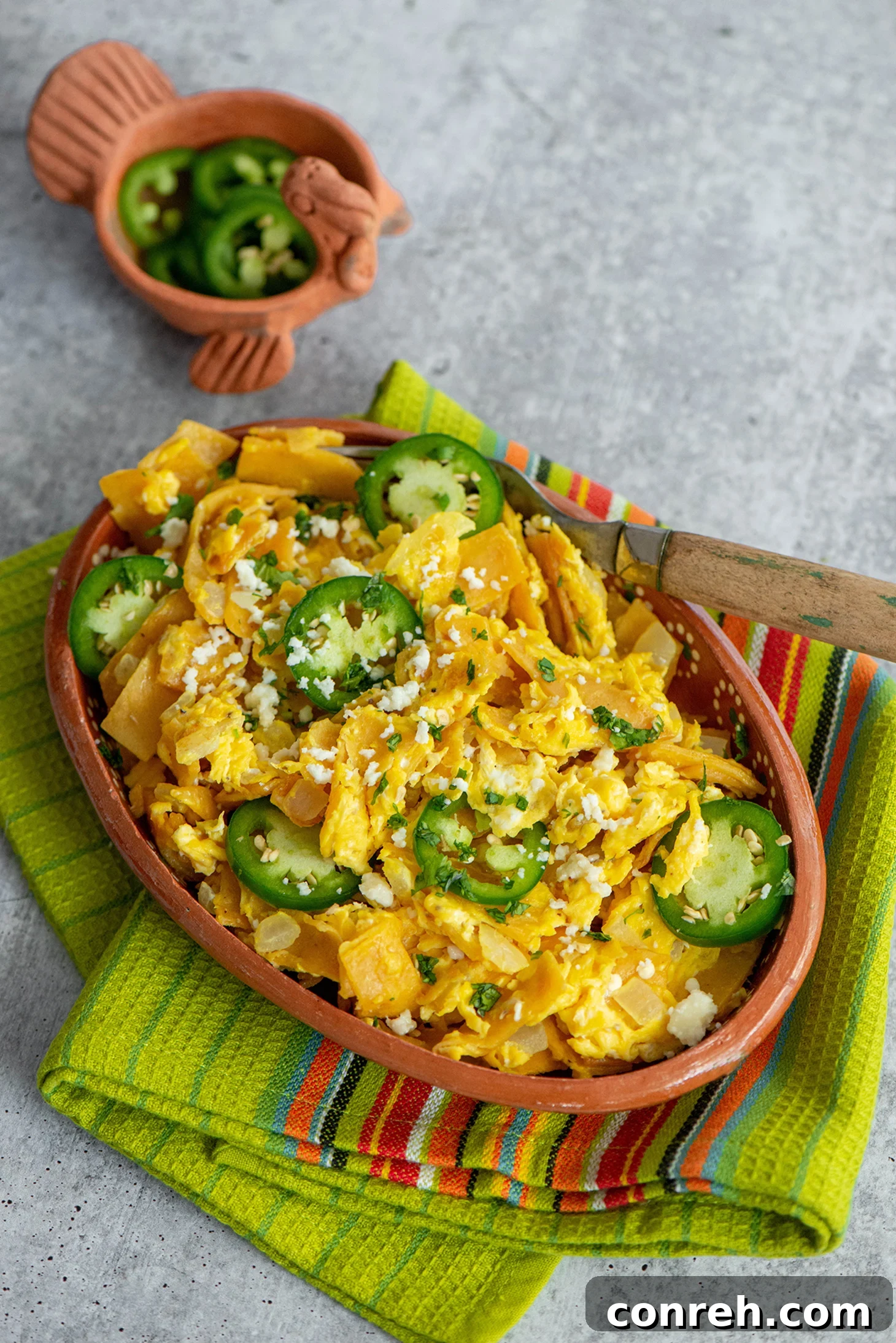 Crumbled Comfort 2 A vibrant plate of Migas, a classic Mexican comfort dish, featuring crispy tortillas scrambled with eggs, topped with fresh jalapeños, cilantro, and crumbled queso fresco.