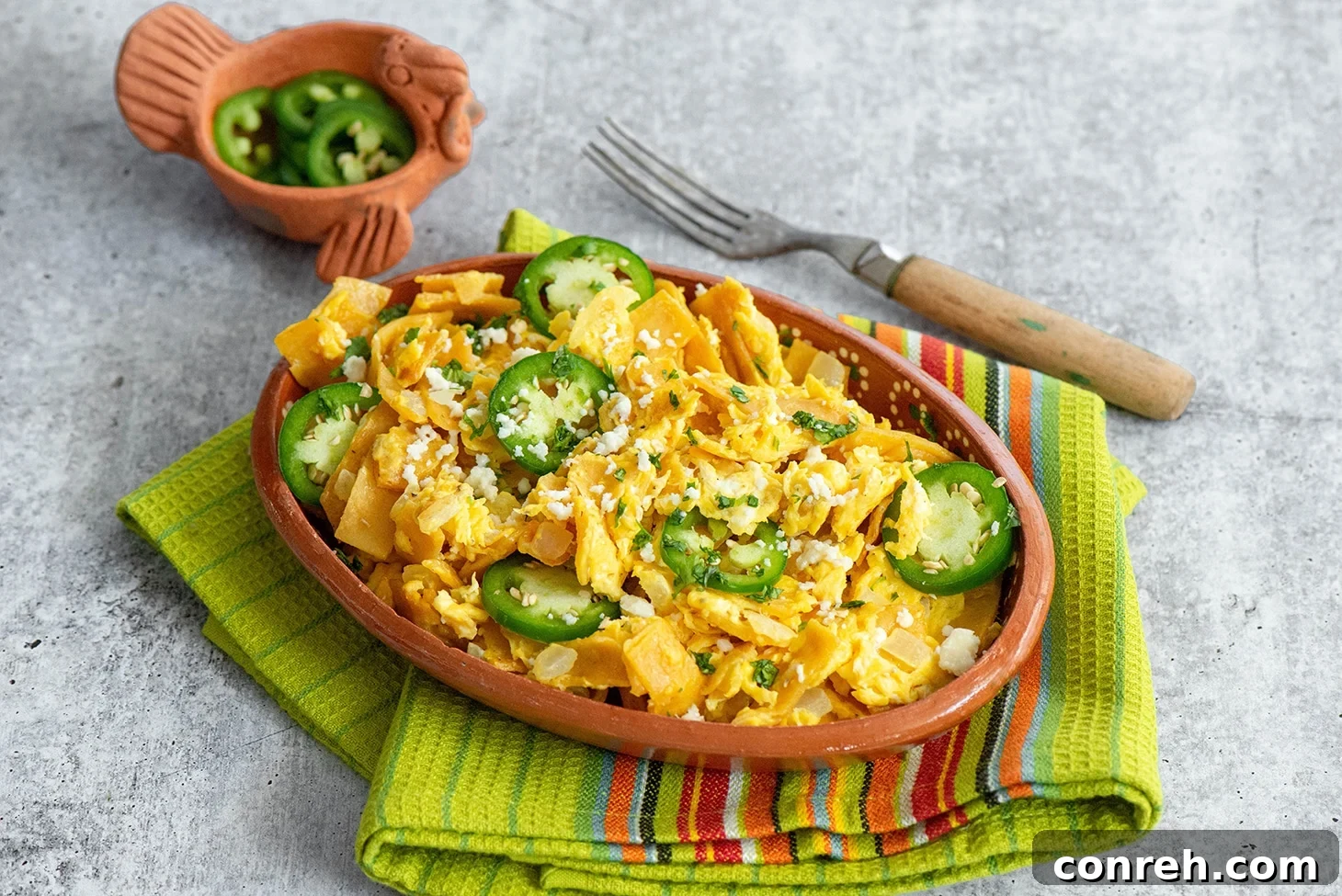 Crumbled Comfort 3 Close-up of freshly cooked Migas in a skillet, showcasing the crispy tortilla pieces, scrambled eggs, and sautéed onions, ready to be served.