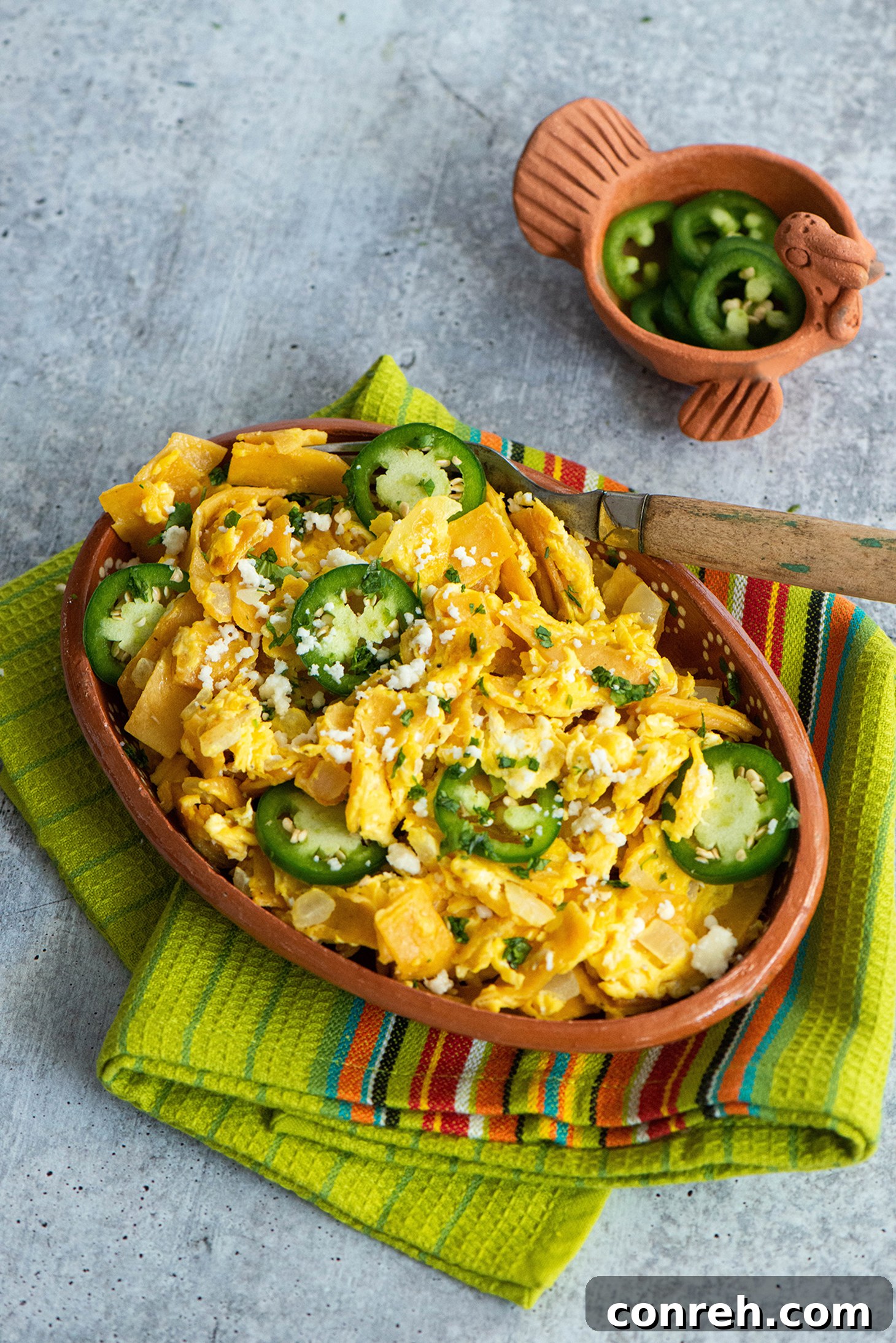 A close-up shot of Migas in a serving bowl, garnished with fresh cilantro and a lime wedge, ready to be enjoyed.