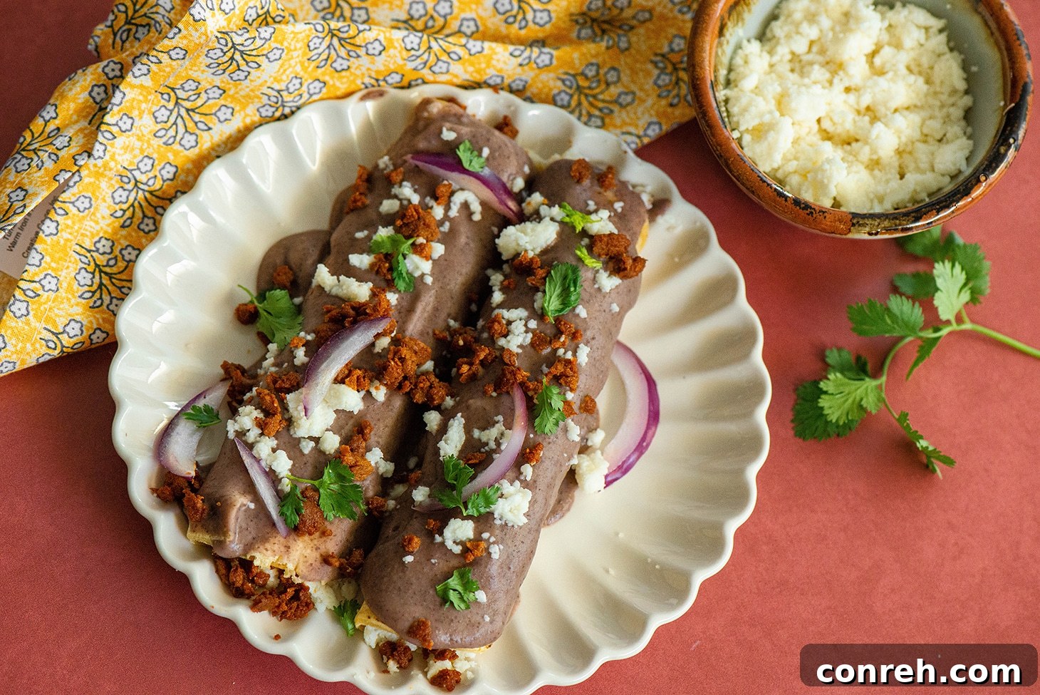 A serving of Queso Fresco Enfrijoladas, showcasing the rich black bean sauce and crumbled cheese.