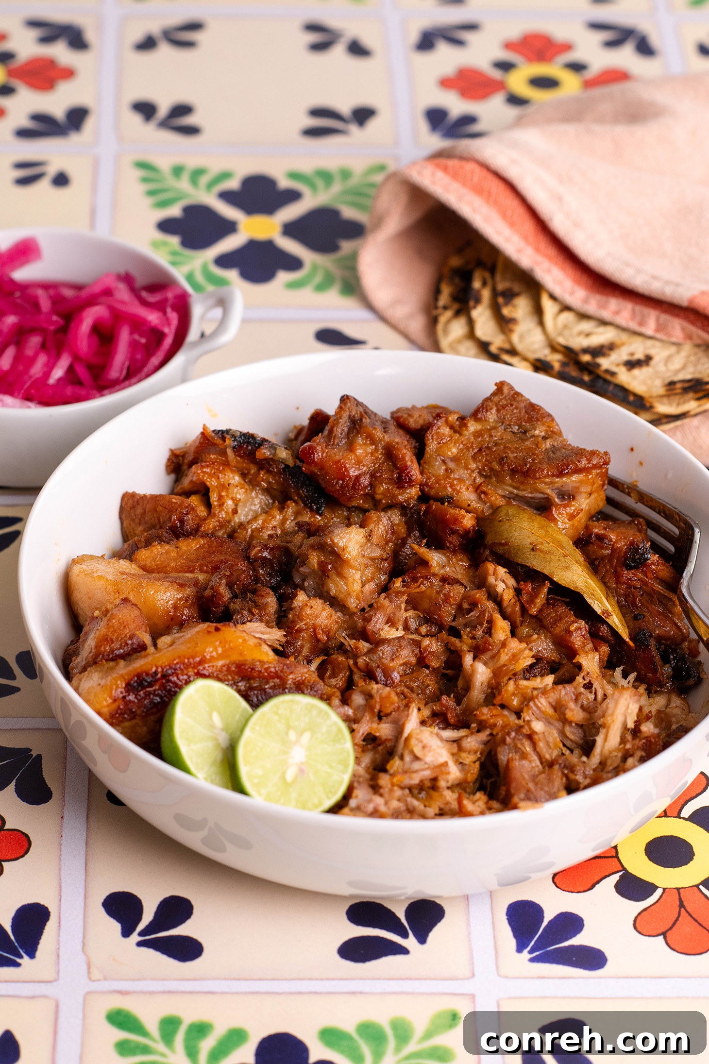 Various carnitas toppings: diced onions, cilantro, lime wedges, and salsa