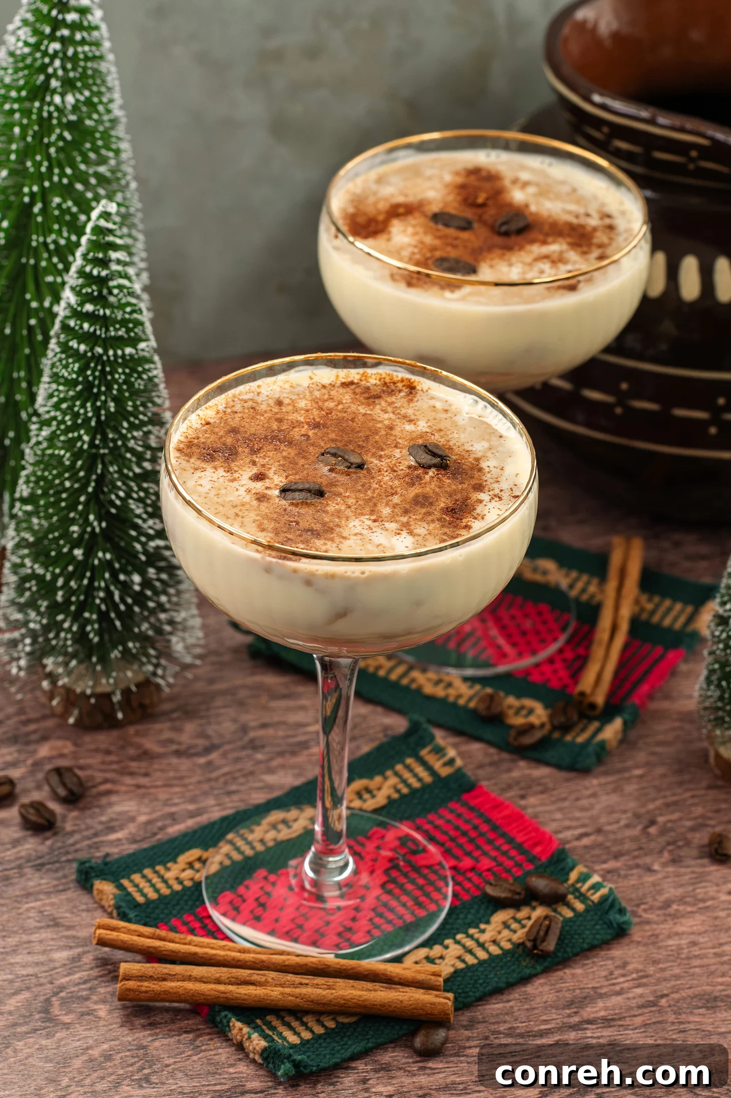 A festive glass of Cafe de Olla Eggnog, garnished with cinnamon and coffee beans, set against a warm, inviting backdrop.