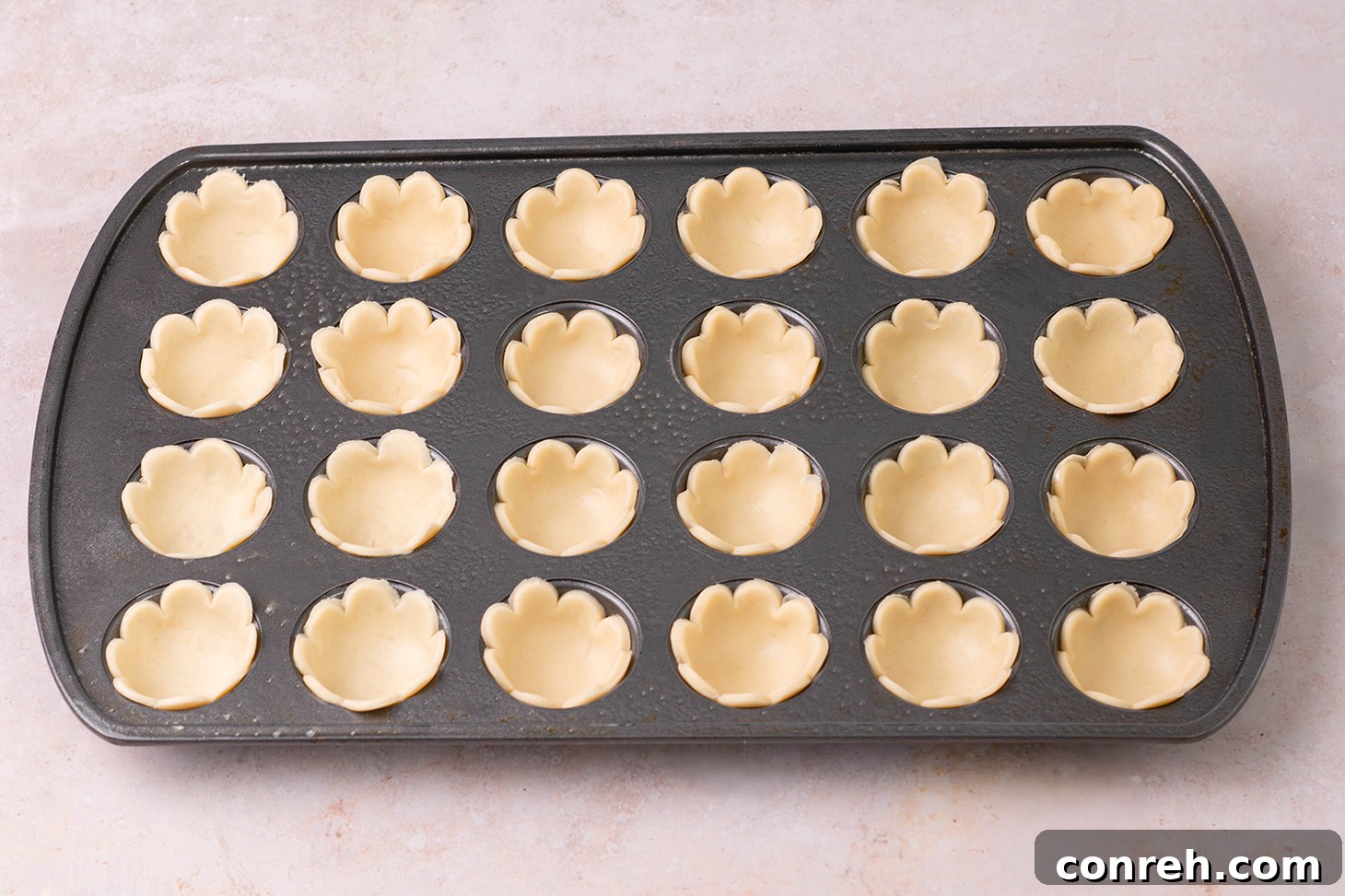 Placing pie crust circles into a mini muffin pan.