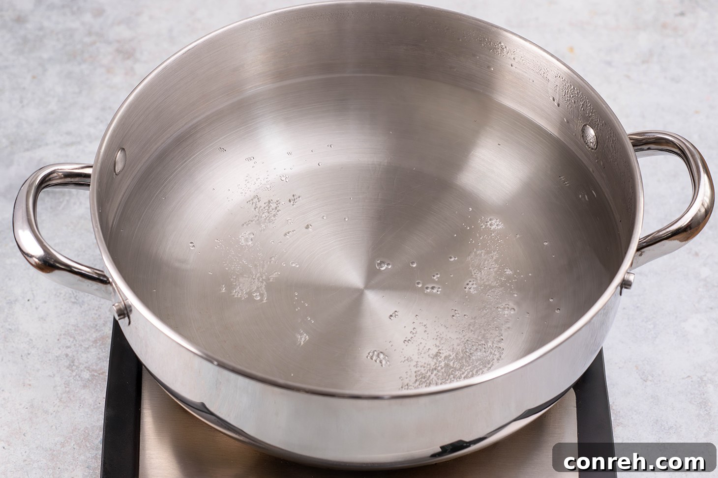 Saucepan filled with water on the stove, beginning to simmer.