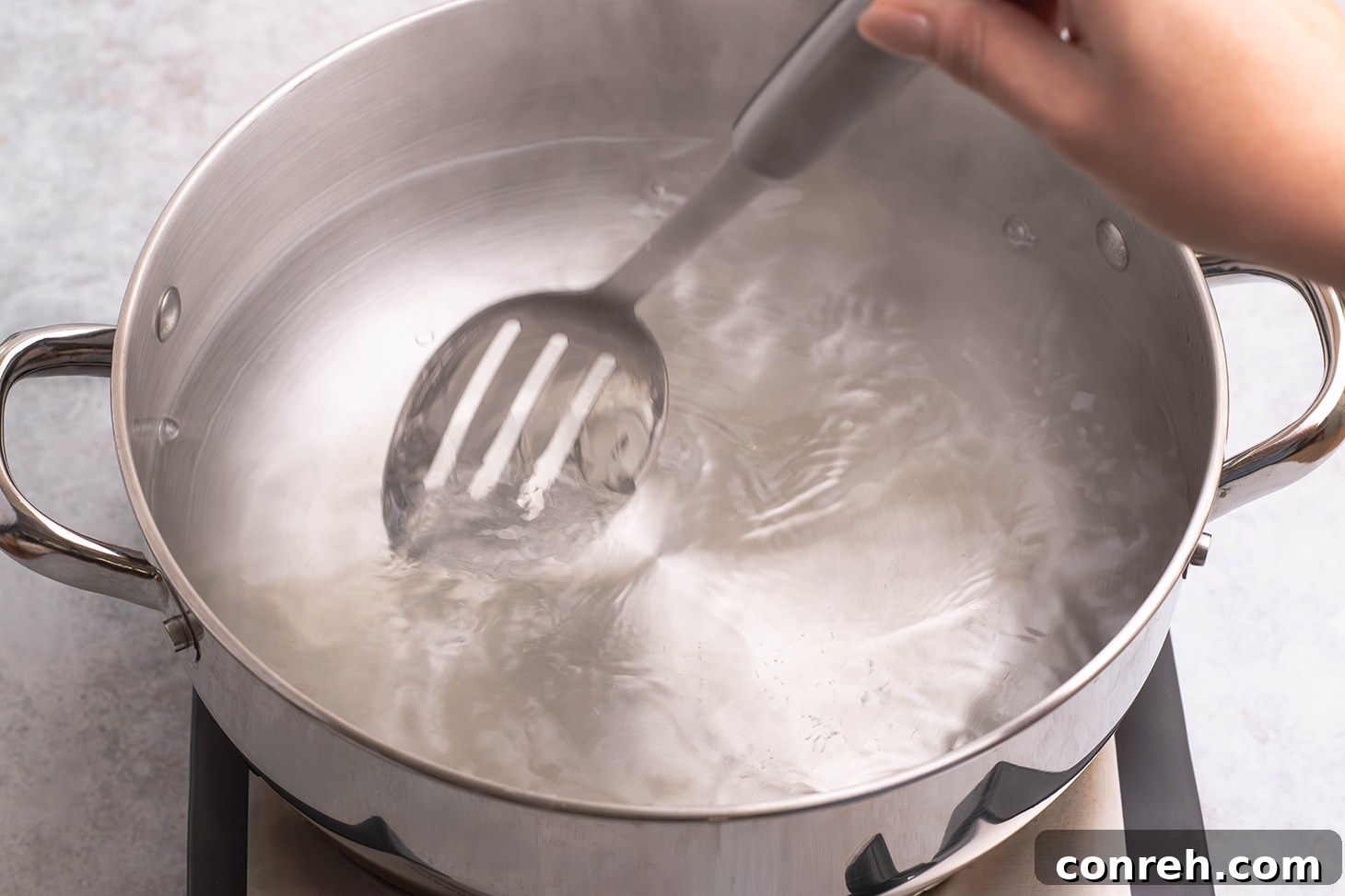 Creating a gentle whirlpool in the simmering water with a spoon.