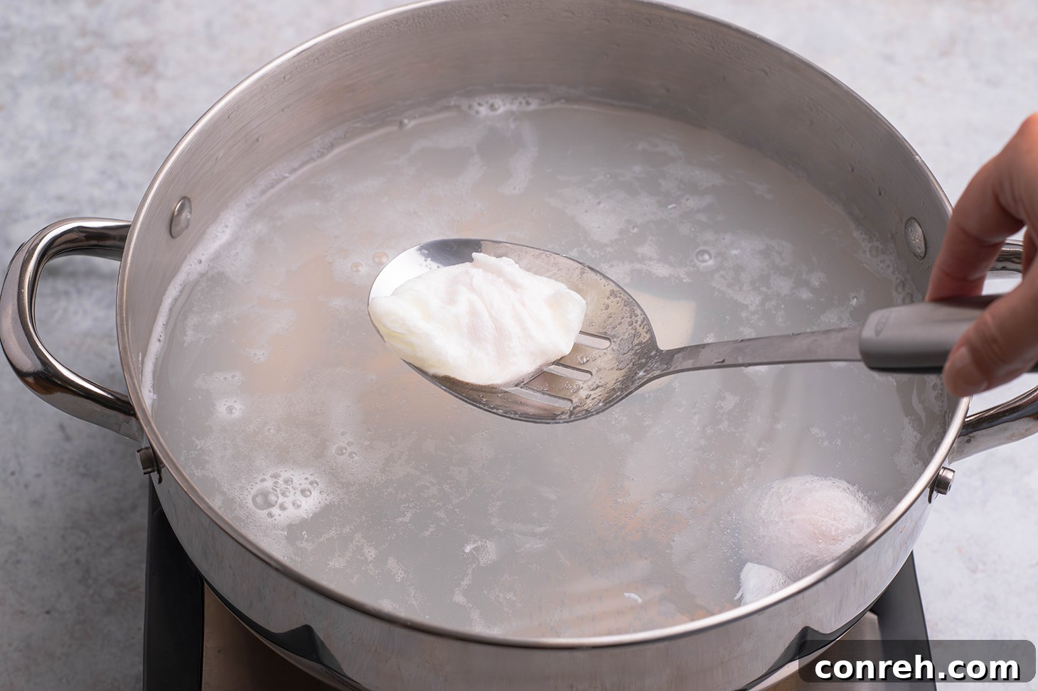 Lifting a perfectly poached egg out of the water with a slotted spoon.